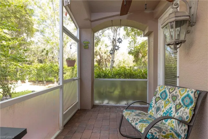 Screened outdoor patio featuring brick paver flooring, an arched ceiling, and an exterior wall light fixture