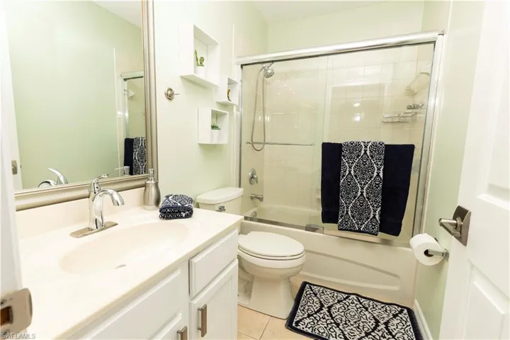 Bathroom featuring a single vanity with an integrated sink, chrome faucet, and white cabinetry