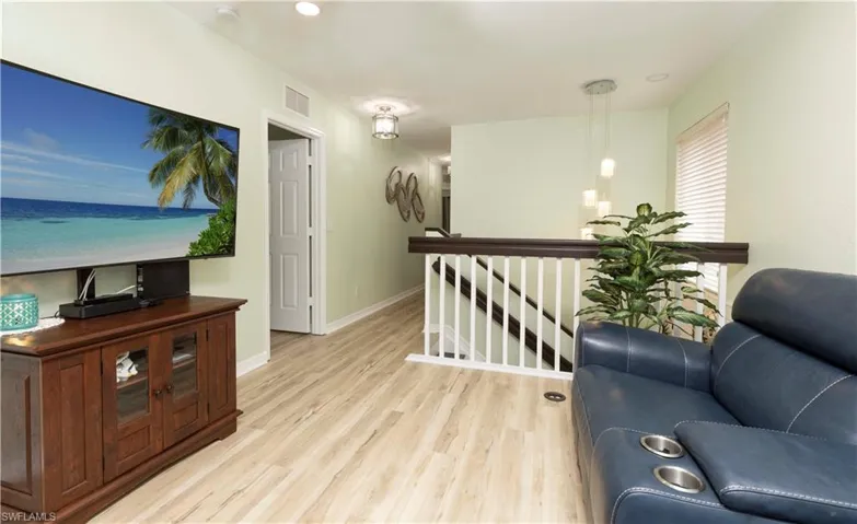 Upper-level landing featuring wood-finish flooring, a white spindle staircase with dark wood railing, and recessed lighting