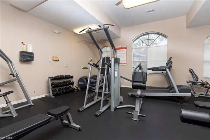 Fitness room featuring rubberized flooring, arched window, ceiling fan, and recessed lighting