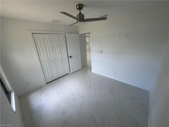 Room featuring large format marble-look tile flooring, a contemporary ceiling fan, and a bi-fold closet with panel doors