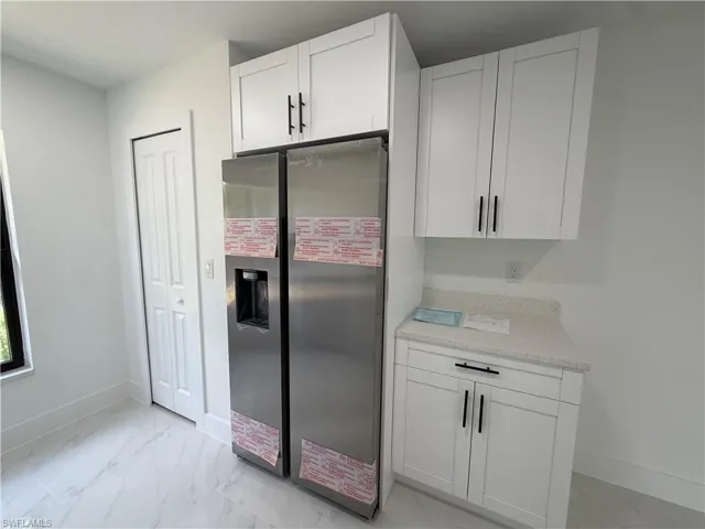 Kitchenette featuring white shaker-style cabinetry, a stainless steel refrigerator, and light-toned countertops