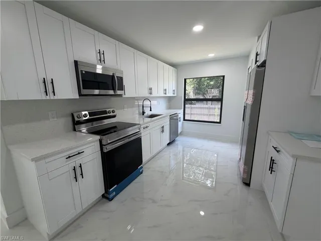 Contemporary kitchen featuring white shaker cabinetry, stainless steel appliances, light-toned countertops, a white subway tile backsplash, and polished porcelain tile flooring