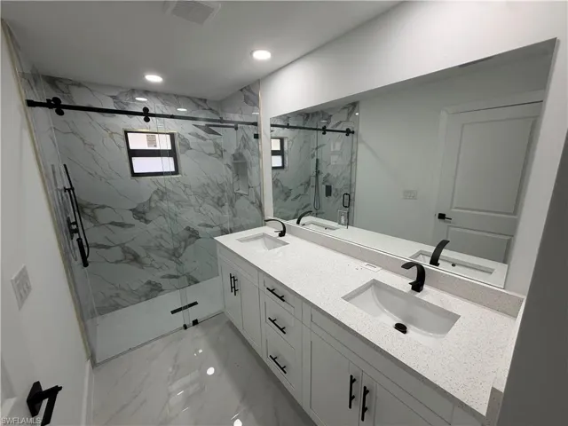 Contemporary bathroom featuring a dual vanity with white cabinetry and integrated sinks, complemented by dark-toned fixtures and a full-width mirror