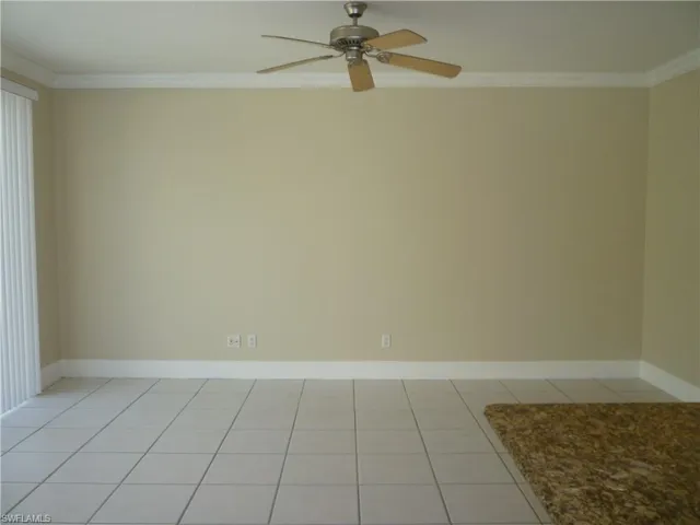 Unfurnished family room with light tile flooring, ornamental molding, and ceiling fan