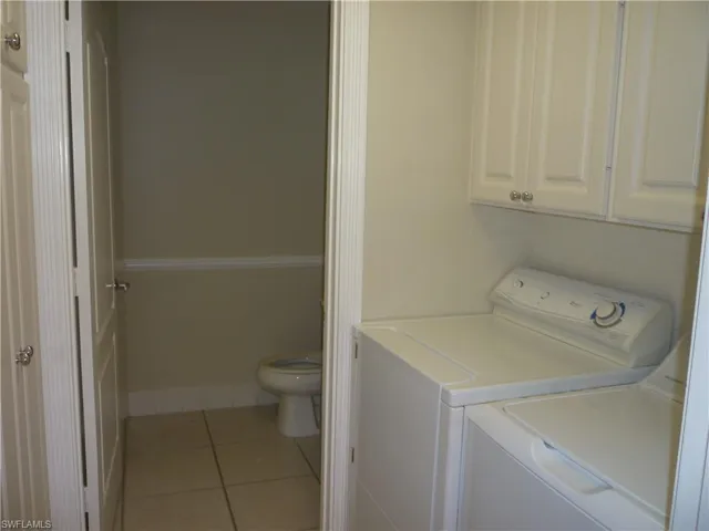 Laundry area featuring light tile patterned floors, cabinet space, and washer and dryer