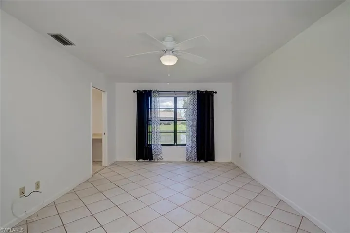 Primary room with light tile patterned floors and ceiling fan