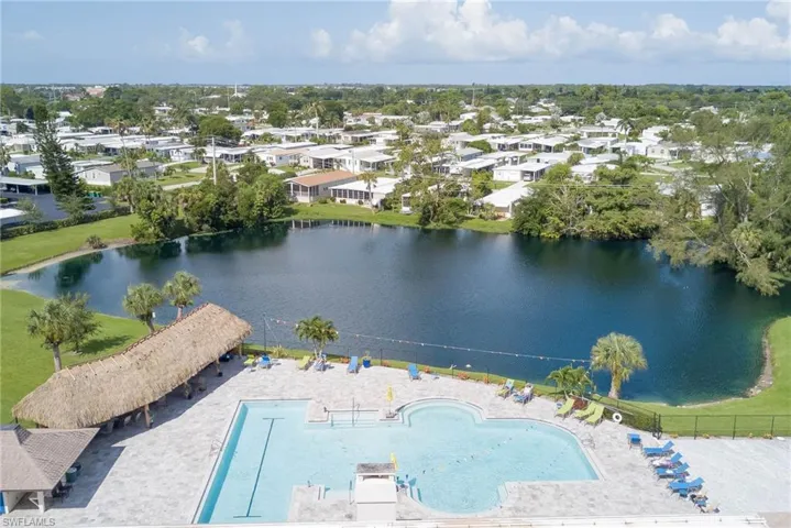 Aerial perspective of clubhouse featuring a nearby body of water and a pool area