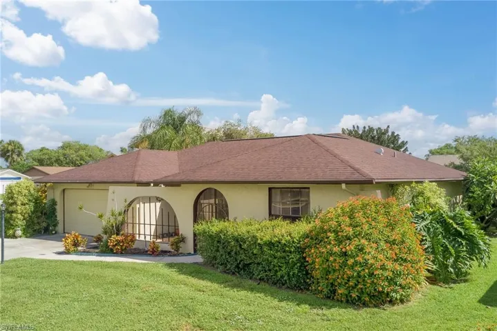 View of front facade featuring a garage, stucco siding, a front lawn, and driveway
