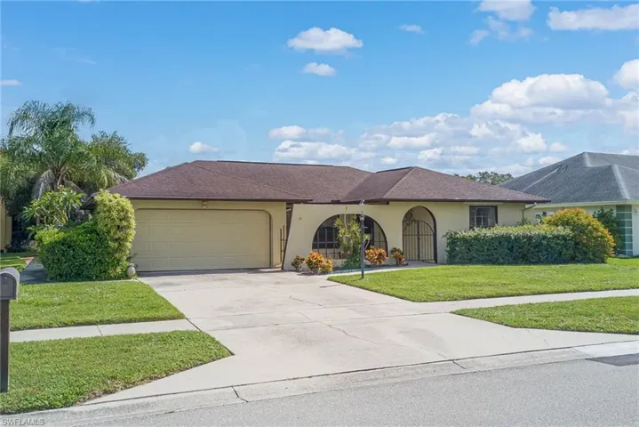 View of front facade with stucco siding, an attached garage, a front lawn, driveway, and roof with shingles