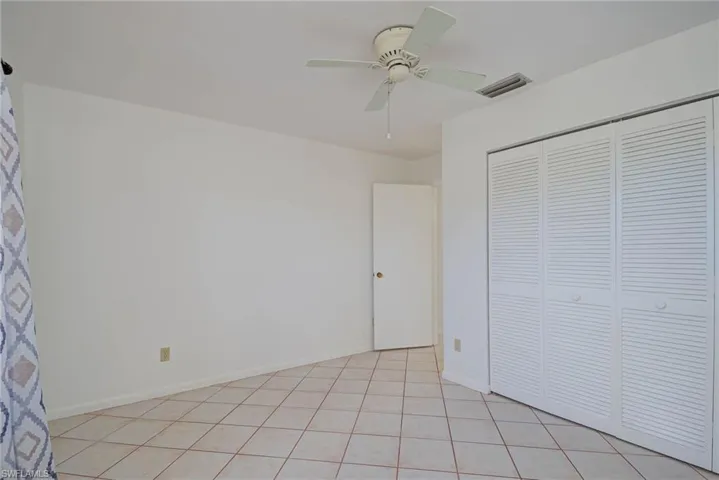 Unfurnished bedroom with a closet, light tile patterned floors, and a ceiling fan