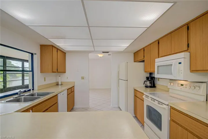 Kitchen featuring white appliances, light countertops, and light tile patterned floors