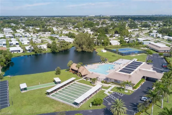 Aerial perspective of clubhouse area with a large body of water, bocce and a pool area