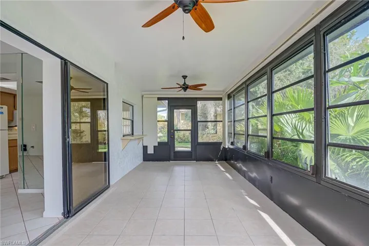 Unfurnished sunroom featuring a ceiling fan and tile patterned floors