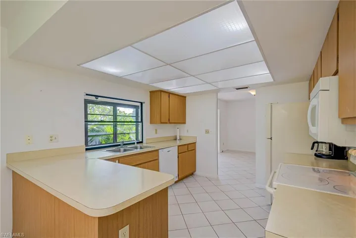 Kitchen featuring light countertops, white appliances, a peninsula, and light tile patterned floors
