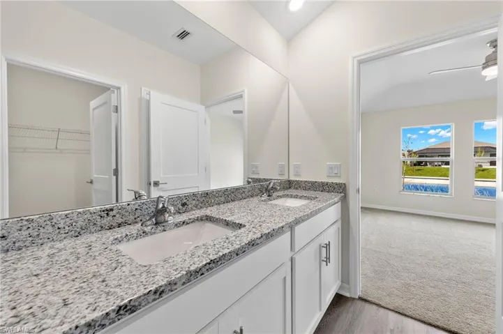Full bathroom featuring a walk in closet, double vanity, a ceiling fan, and light wood-type flooring
