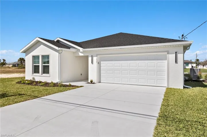 Ranch-style home with a front yard, concrete driveway, a shingled roof, stucco siding, and an attached garage