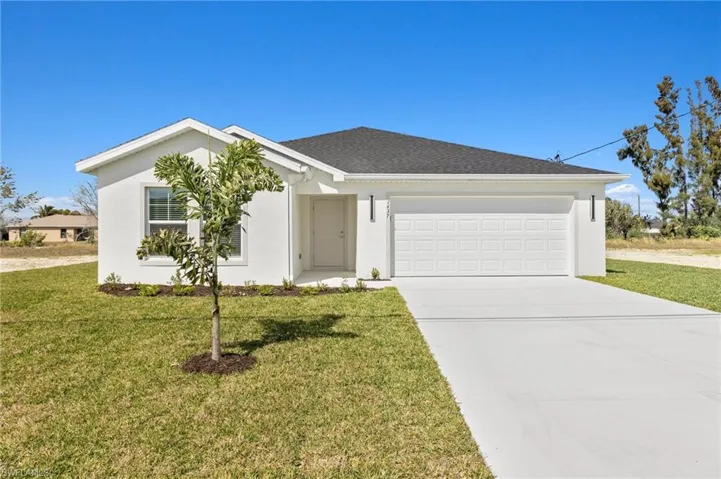 Single story home featuring driveway, a front yard, and stucco siding
