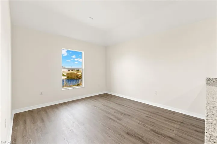 Unfurnished room featuring wood finished floors and lofted ceiling