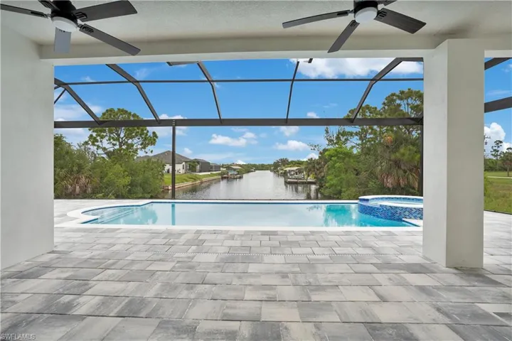 View of pool featuring a pool with connected hot tub, a water view, a sunroom, and a lanai