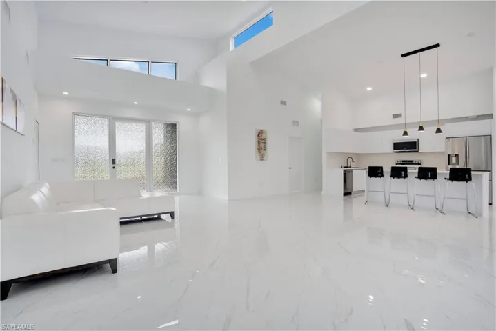 Living room with a high ceiling, light marble finish floors, and recessed lighting