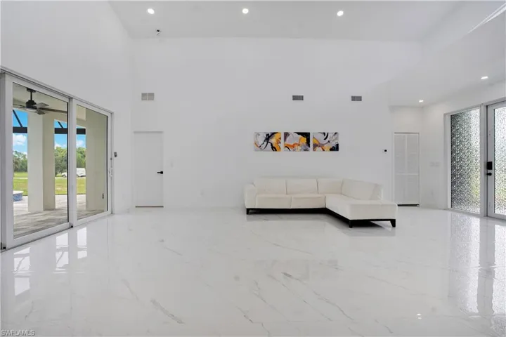 Living room with recessed lighting, light marble finish flooring, french doors, a high ceiling, and ceiling fan