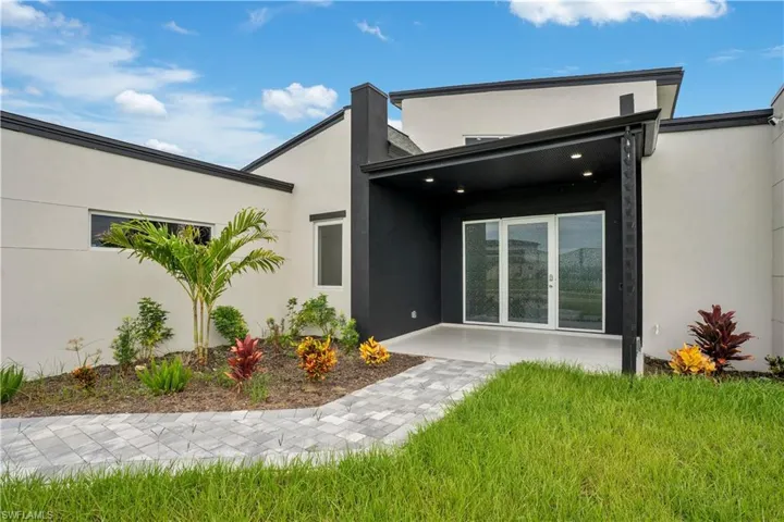 Doorway to property featuring stucco siding and a lawn