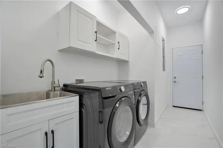 Washroom with light marble finish flooring, washer and dryer, and cabinet space
