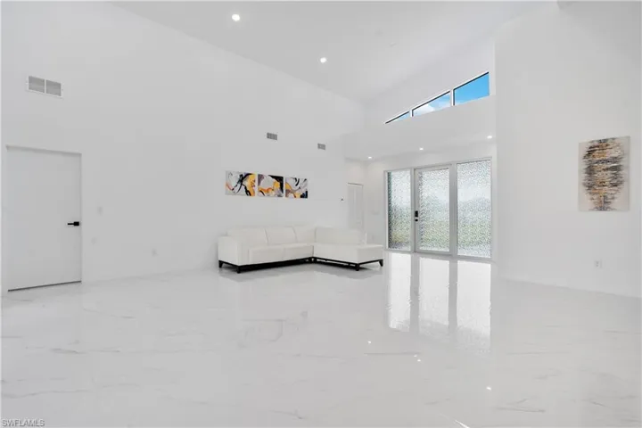 Unfurnished living room with a high ceiling, light marble finish floors, and recessed lighting