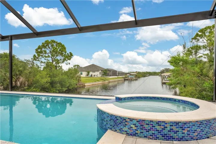 View of swimming pool featuring a water view, a pool with connected hot tub, and a lanai