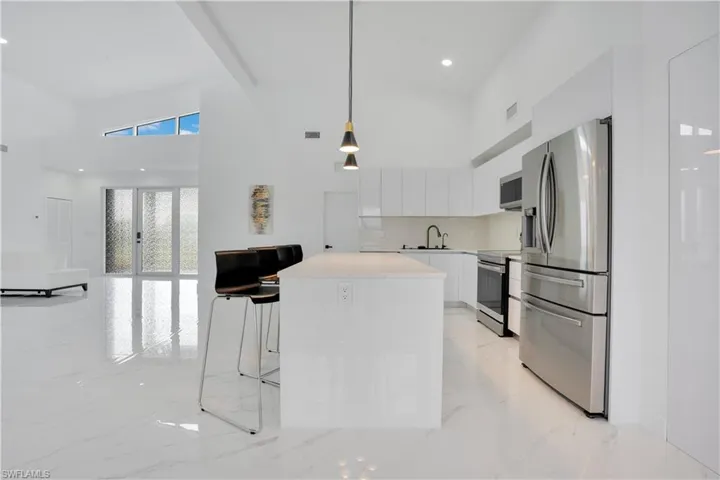 Kitchen with white cabinets, appliances with stainless steel finishes, modern cabinets, pendant lighting, and a kitchen breakfast bar