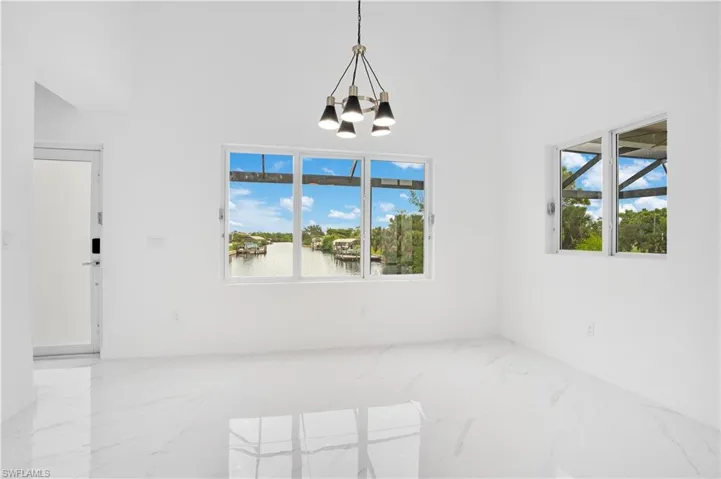 Unfurnished dining area featuring marble tiled floors, plenty of natural light, a water view, and a towering ceiling