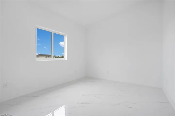 Empty room featuring light marble finish flooring and baseboards