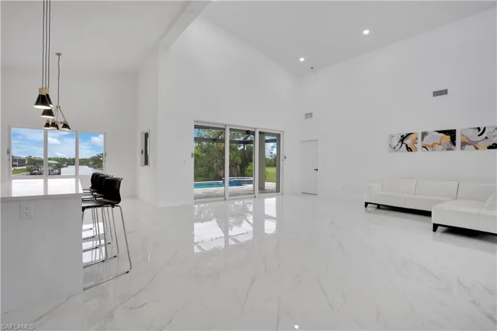 Living area with light marble finish flooring, plenty of natural light, a high ceiling, and recessed lighting
