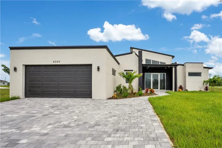 View of front facade with decorative driveway, stucco siding, a front yard, and an attached garage