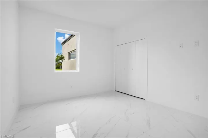 Unfurnished bedroom featuring light marble finish flooring and a closet