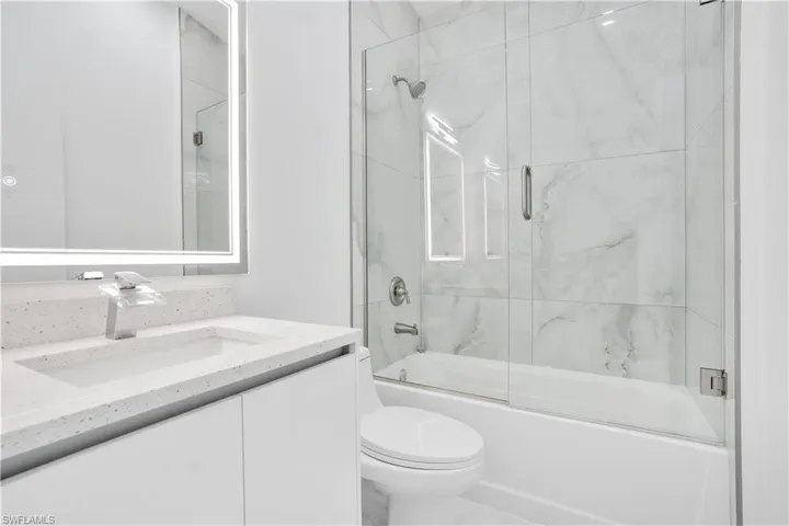 Full bath with vanity and combined bath / shower with glass door