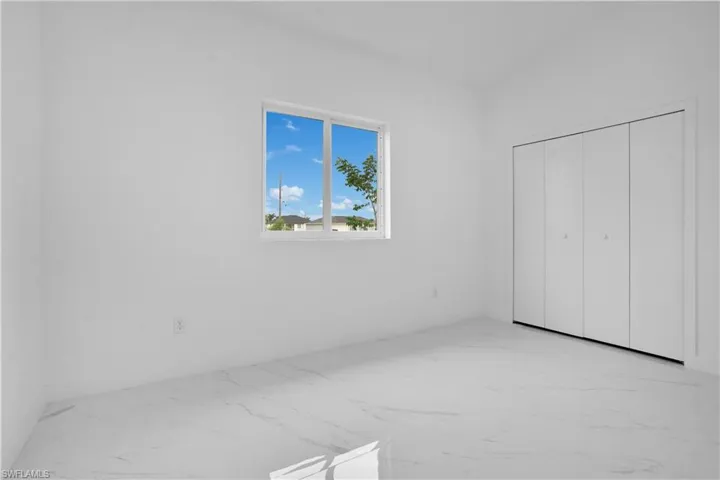 Unfurnished bedroom featuring light marble finish floors and a closet