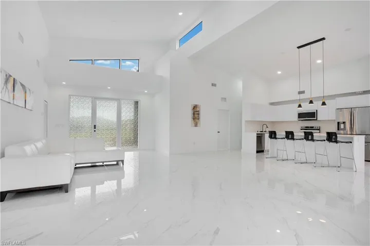Unfurnished living room with light marble finish flooring, a towering ceiling, and recessed lighting