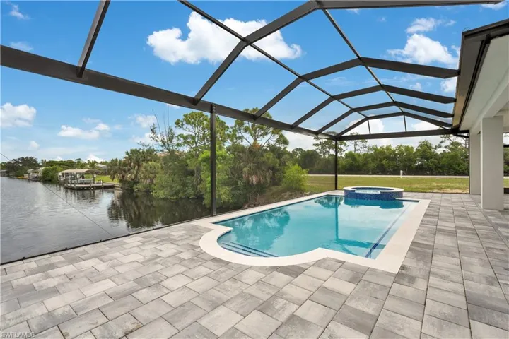 View of swimming pool with glass enclosure, a sunroom, a patio area, and a pool with connected hot tub