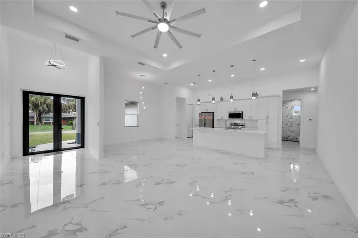 Unfurnished living room with ceiling fan, a raised ceiling, and french doors