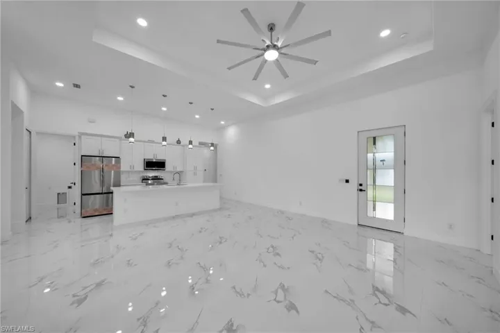 Unfurnished living room with a tray ceiling, sink, and ceiling fan
