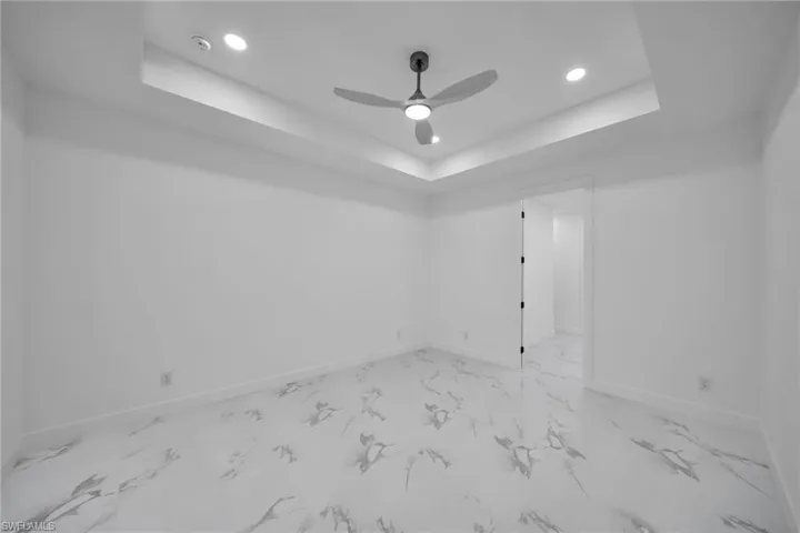 Empty room featuring a raised ceiling and ceiling fan