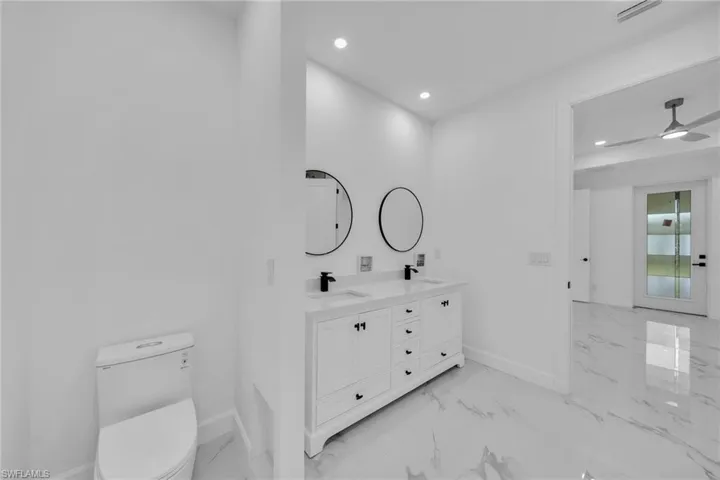 Bathroom featuring vanity, toilet, and ceiling fan
