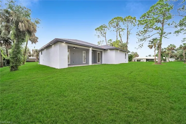 Back of house with a patio area, a lawn, and ceiling fan