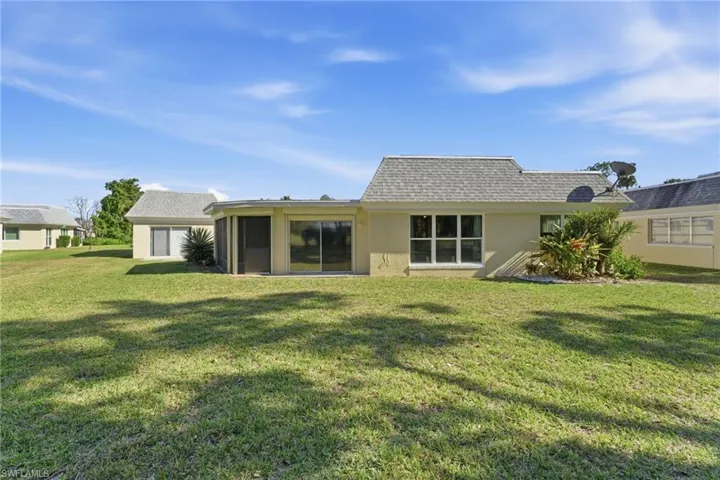 Back of property with roof with shingles, a lawn, a sunroom, and stucco siding