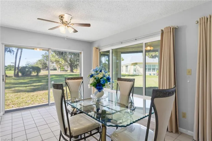 Dining room with a textured ceiling, light tile patterned floors, plenty of natural light, and a ceiling fan