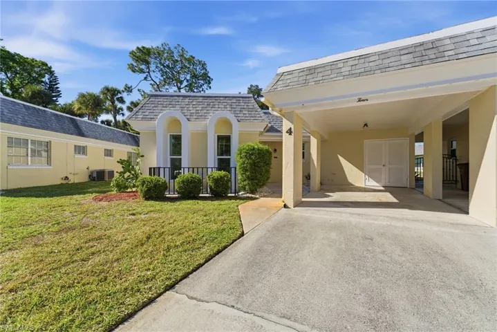 View of front of home with a shingled roof, driveway, mansard roof, a front lawn, and a carport