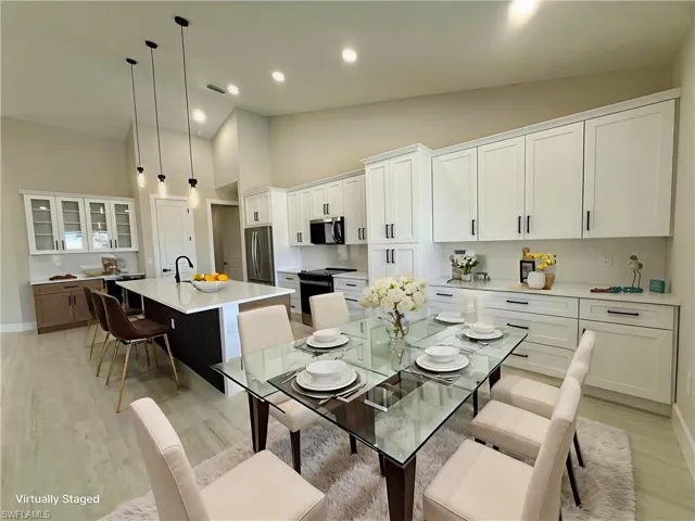 Kitchen with lofted ceiling, open floor plan, stainless steel appliances, a center island with sink, and a ceiling fan