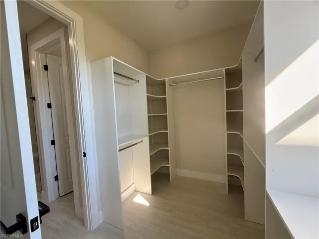 Walk in closet with light wood-style flooring